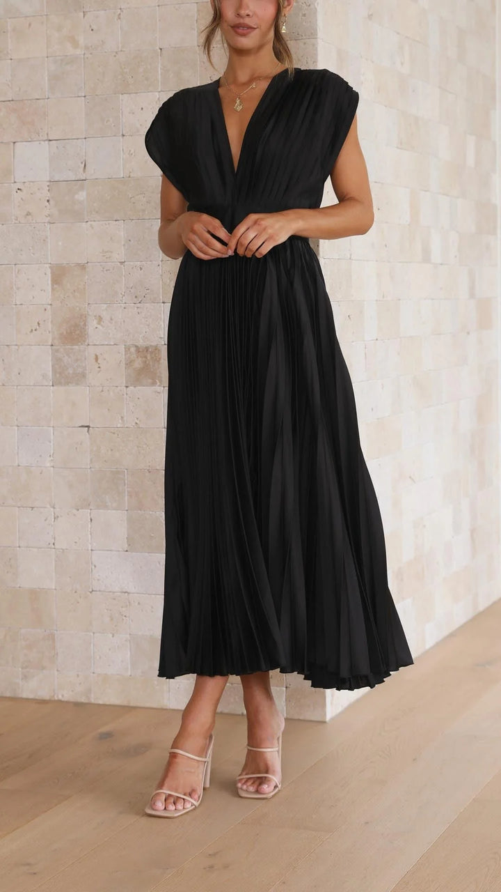 Woman wearing flowing pleated maxi dress in neutral setting