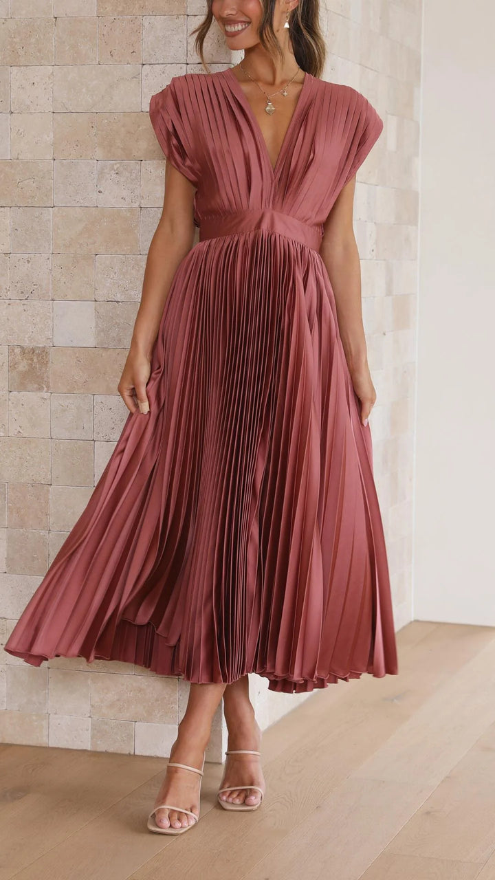 Side angle of flowing pleated maxi dress with V-neckline and lightweight fabric drape