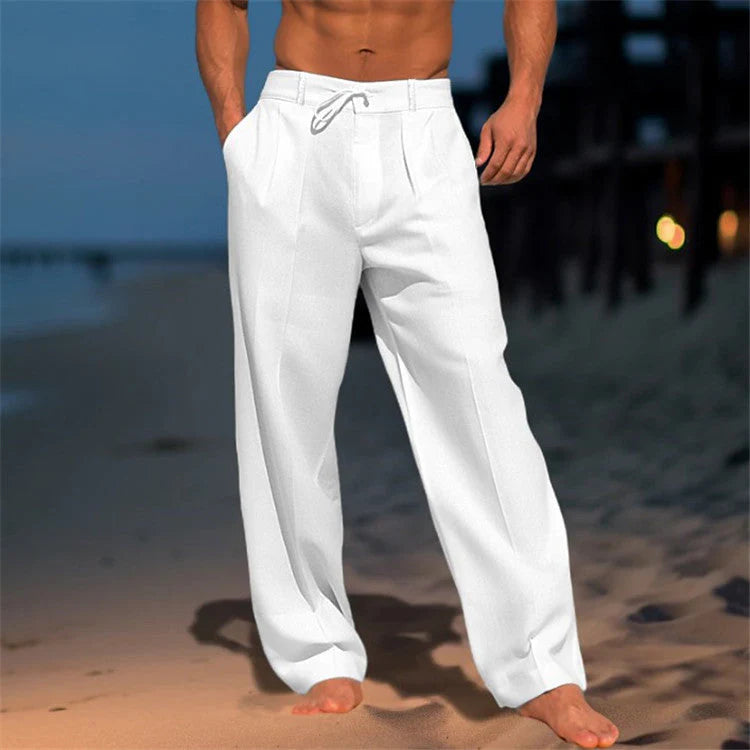 Men's relaxed drawstring pants in white with straight leg and pleated front on beach