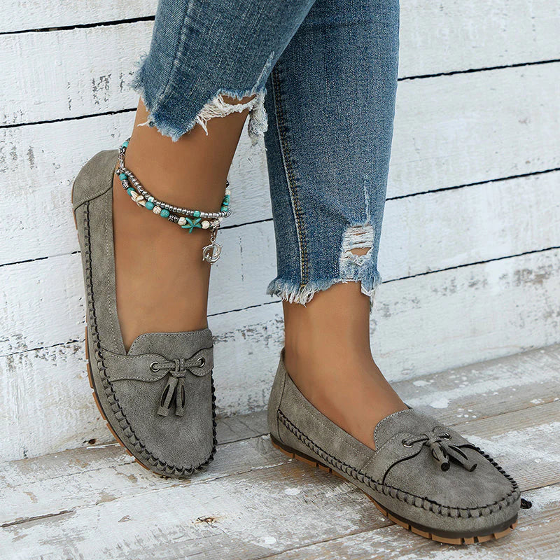 Side profile of women's slip-on loafers showing bow detail and flexible upper