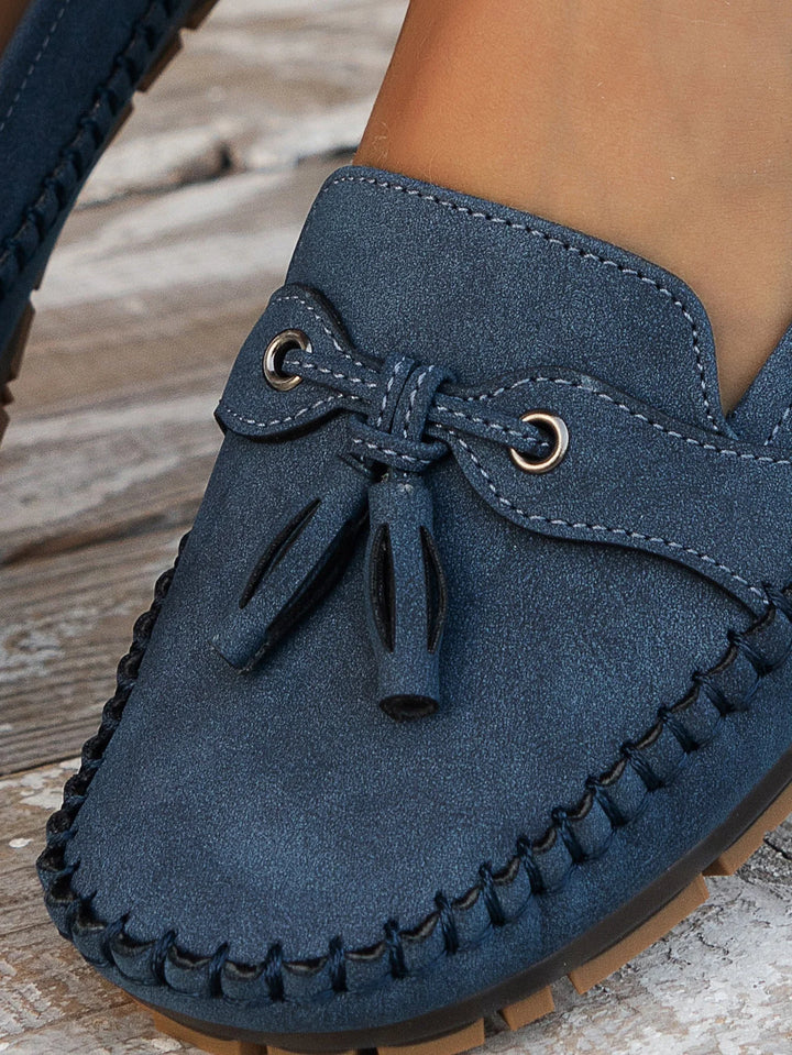 Detail of slip-on loafer showing smooth synthetic material and hand-stitched trim