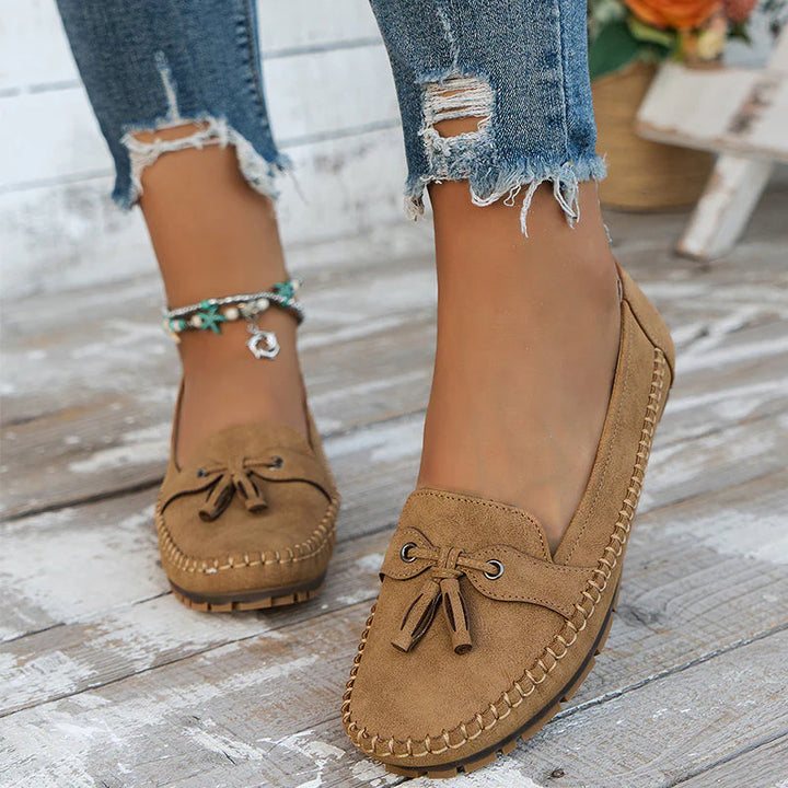 Women's orthopedic loafers worn with distressed jeans on outdoor wooden deck setting