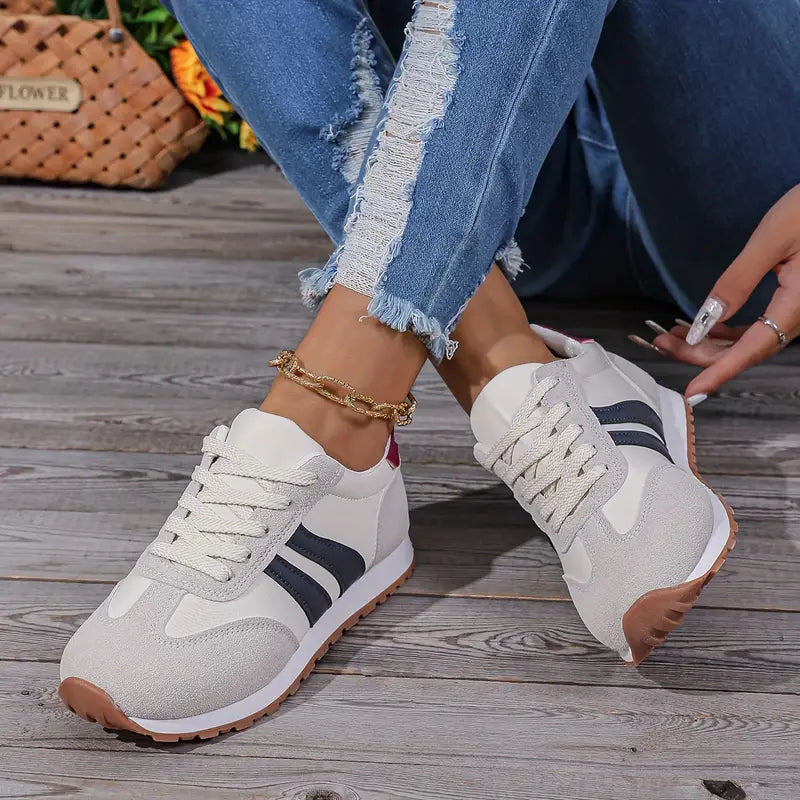 Close-up of gray and white sneakers showing textured suede panels and gum rubber outsole tread
