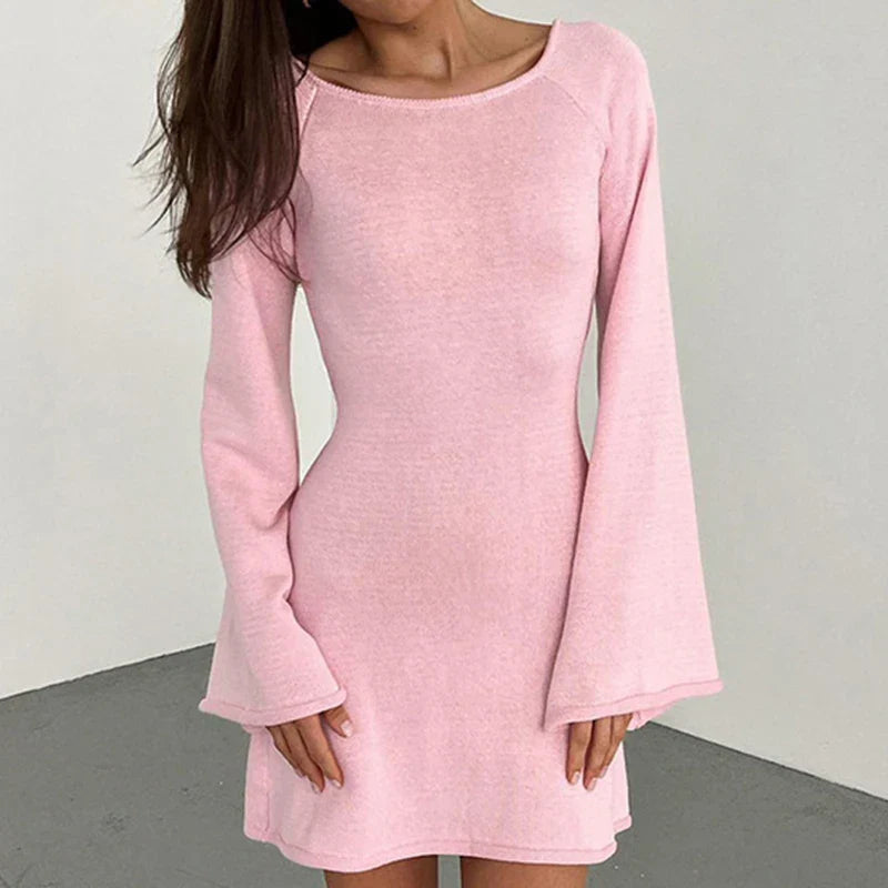 Woman wearing pink long-sleeve mini dress with wide neckline and flared cuffs in above-the-knee length