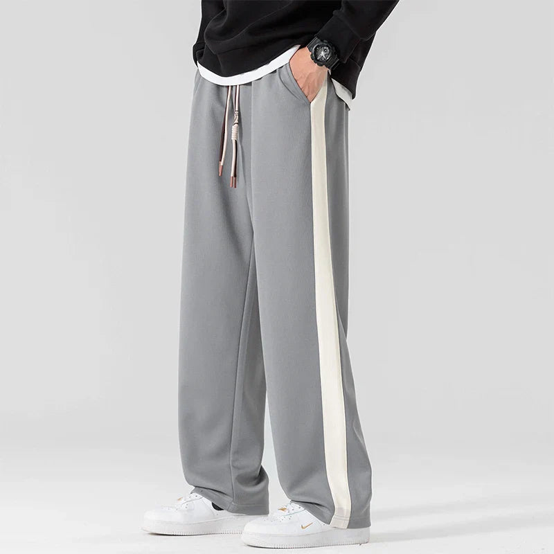 Side view of men's relaxed fit sweatpants showing full length stripe and wide leg silhouette