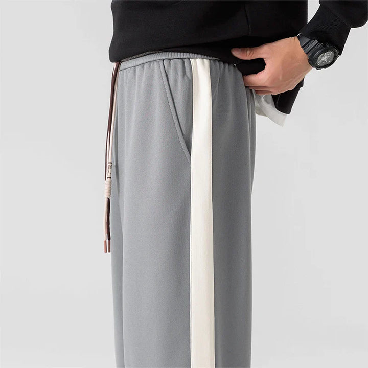 Men's black wide leg sweatpants paired with white sneakers showing relaxed fit and straight leg