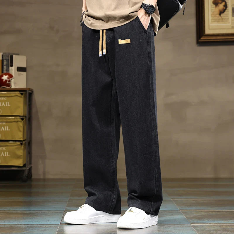 Full-length view of men's casual wide leg jeans paired with white sneakers for streetwear styling