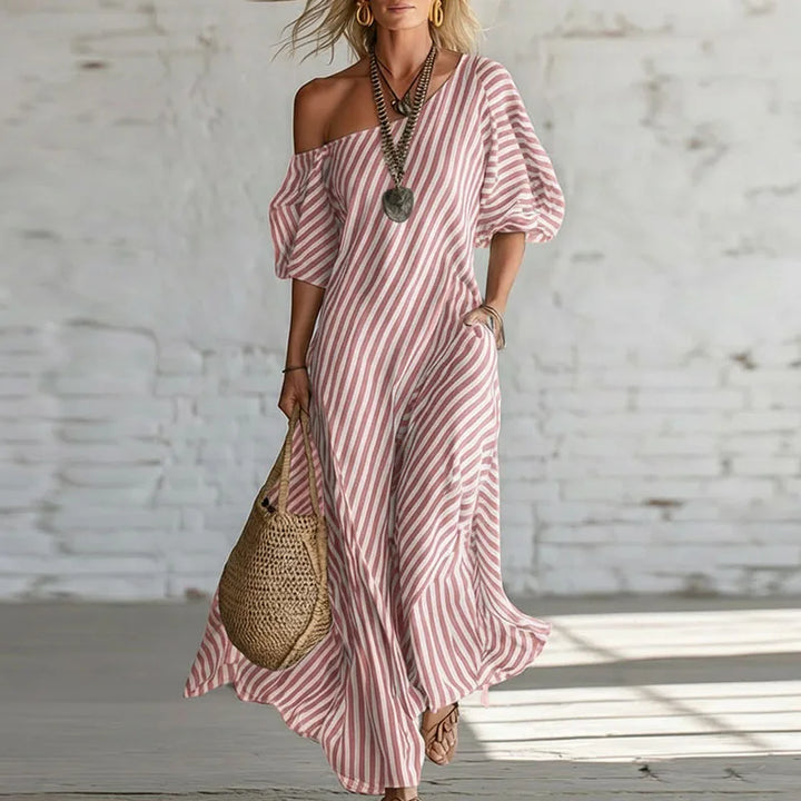 Woman wearing pink and white striped one shoulder puff sleeve dress with flowing maxi length and asymmetric neckline