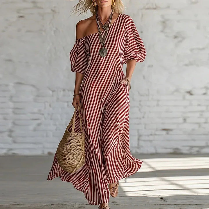Close-up of gathered puff sleeve detail on one shoulder striped maxi dress with flowing fabric