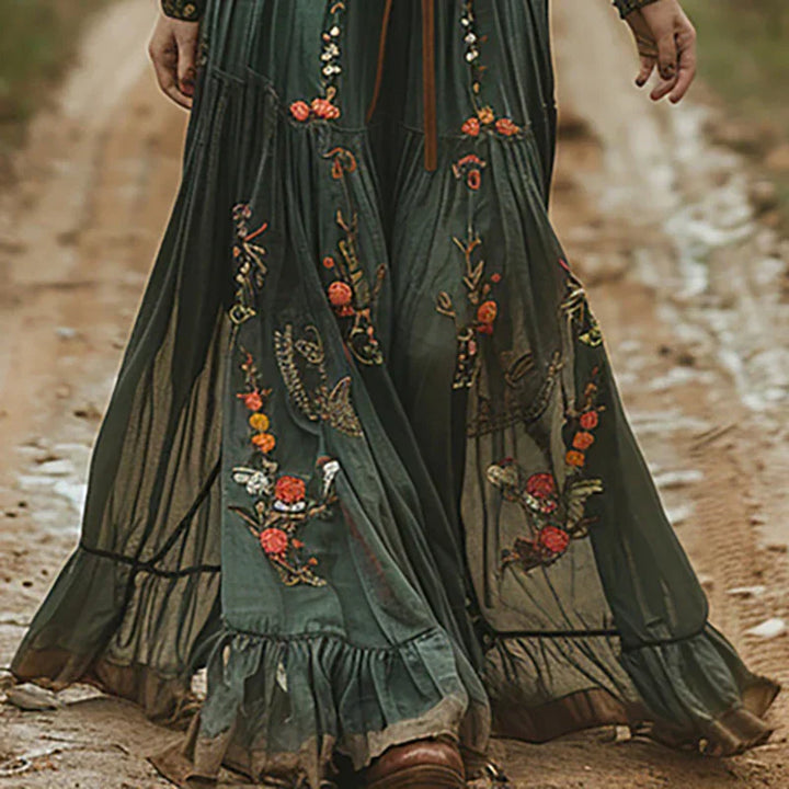 Embroidered maxi dress in dark brown showing bohemian style with sheer sleeves and tiered hem