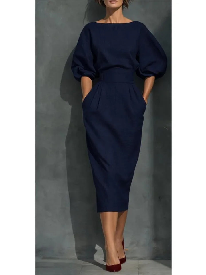 Back view of midi dress with pleated skirt and boat neckline in solid color
