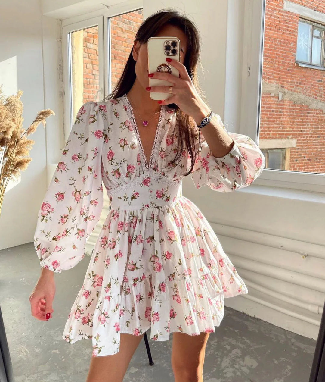 Woman wearing a Floral Mini Dress Long Puff Sleeves V-Neck with lace trim and tiered skirt in a bright interior setting