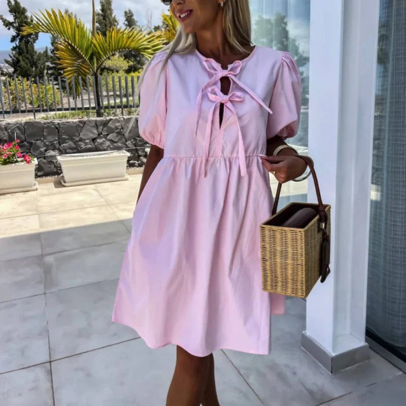Mini dress with puff sleeves and bow detail at chest showing flared silhouette and cut-out design