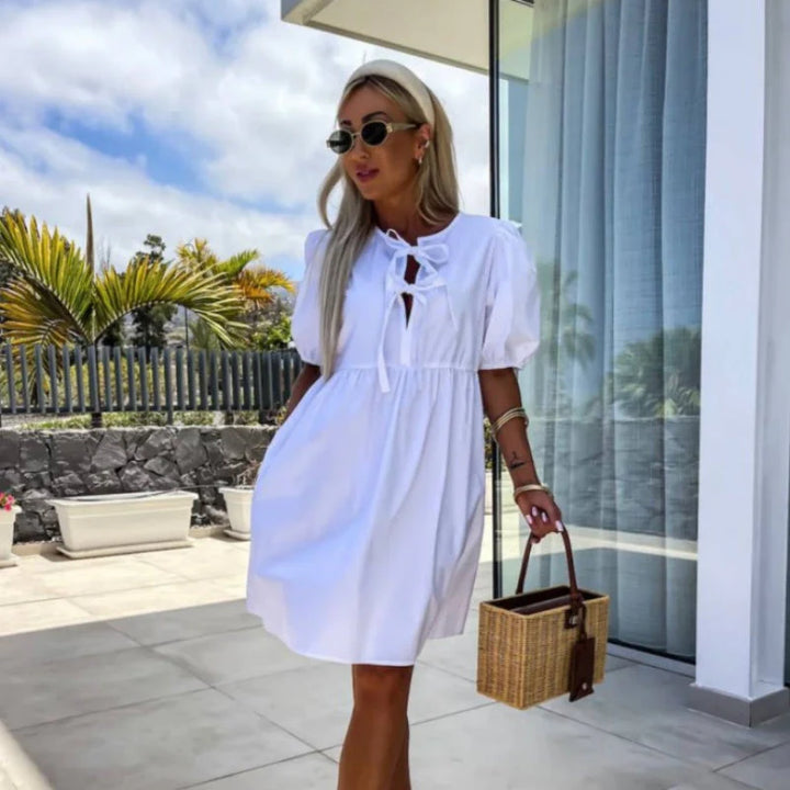 Above-the-knee mini dress featuring short puff sleeves and defined waist seam in solid color