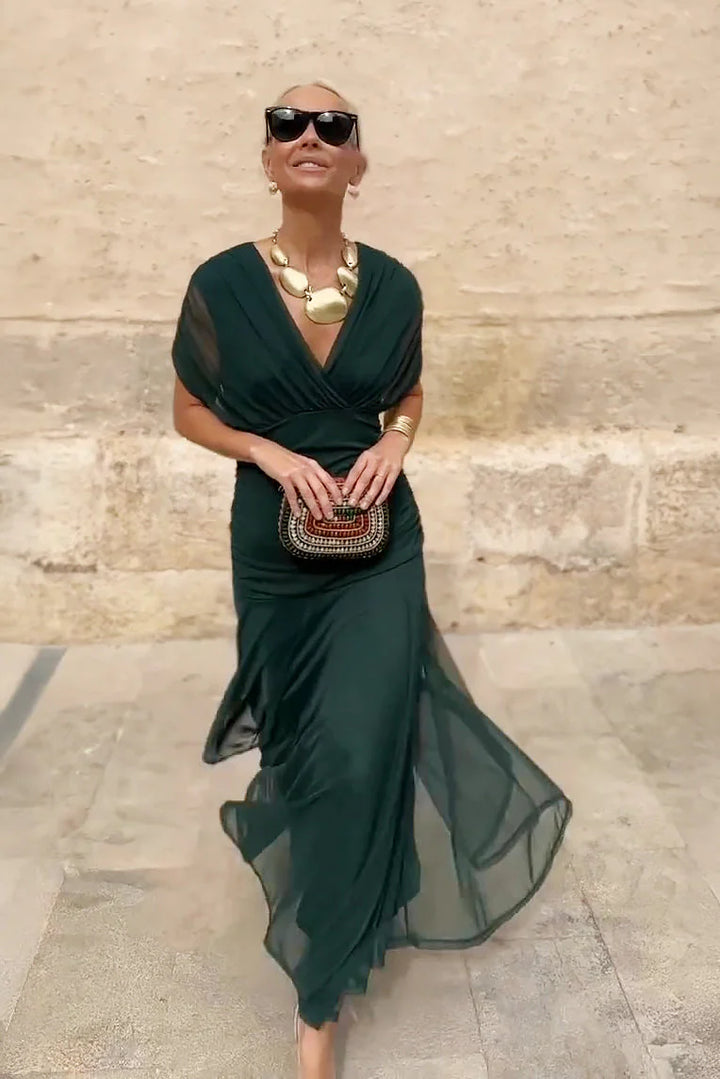 Side view of maxi ceremony dress showing draped sleeve detail and pleated waist construction
