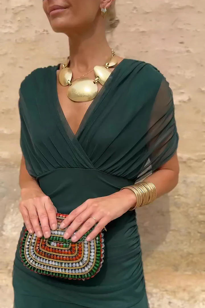 Close-up of V-neck bodice on maxi ceremony dress with wrapped front and sheer mesh sleeves