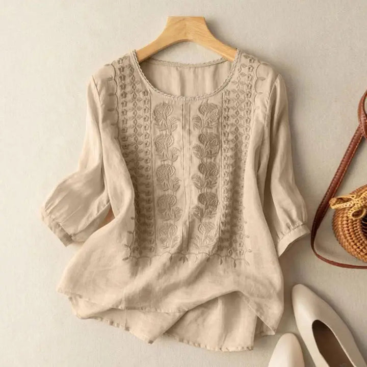 Close-up view of embroidered floral and geometric detailing on women's linen blouse front bodice