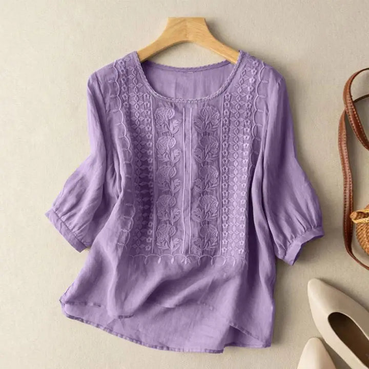 Women's embroidered linen blouse styled with white pumps and woven crossbody bag