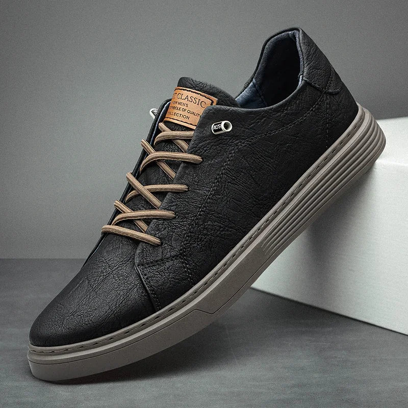 Men's black low-top sneakers with tan laces and ridged sole on neutral background