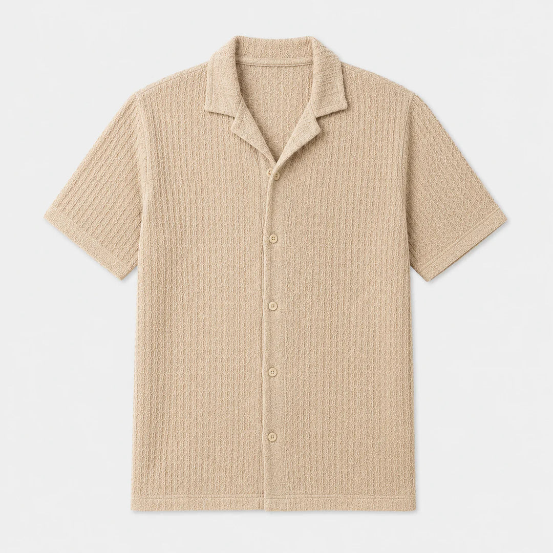 Men's beige short sleeve camp collar shirt with textured knit fabric and button-front closure on white background