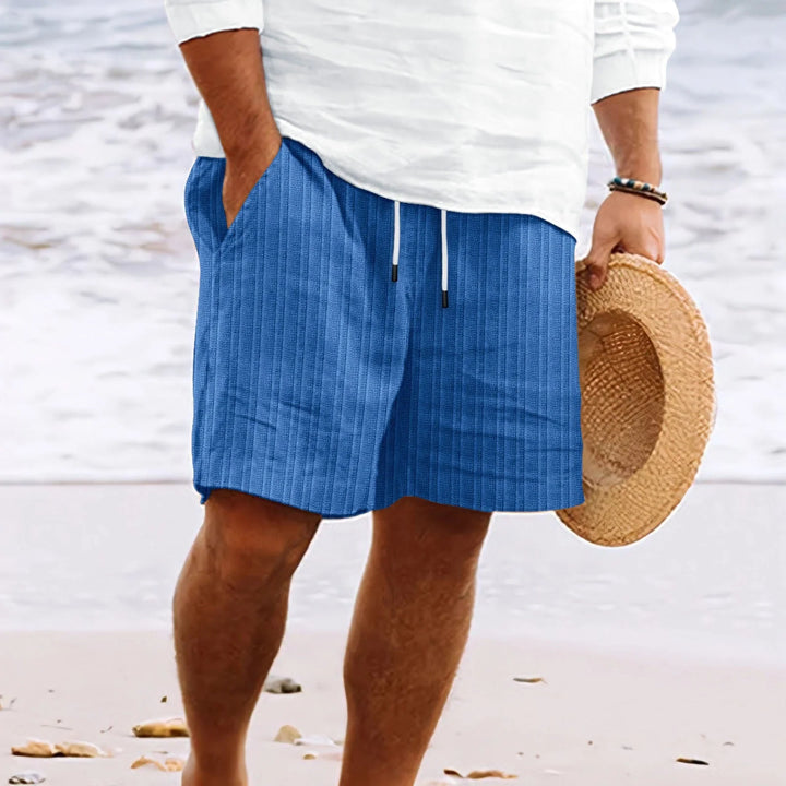 Men's drawstring chino shorts styled with white shirt on beach showcasing casual summer outfit and relaxed silhouette