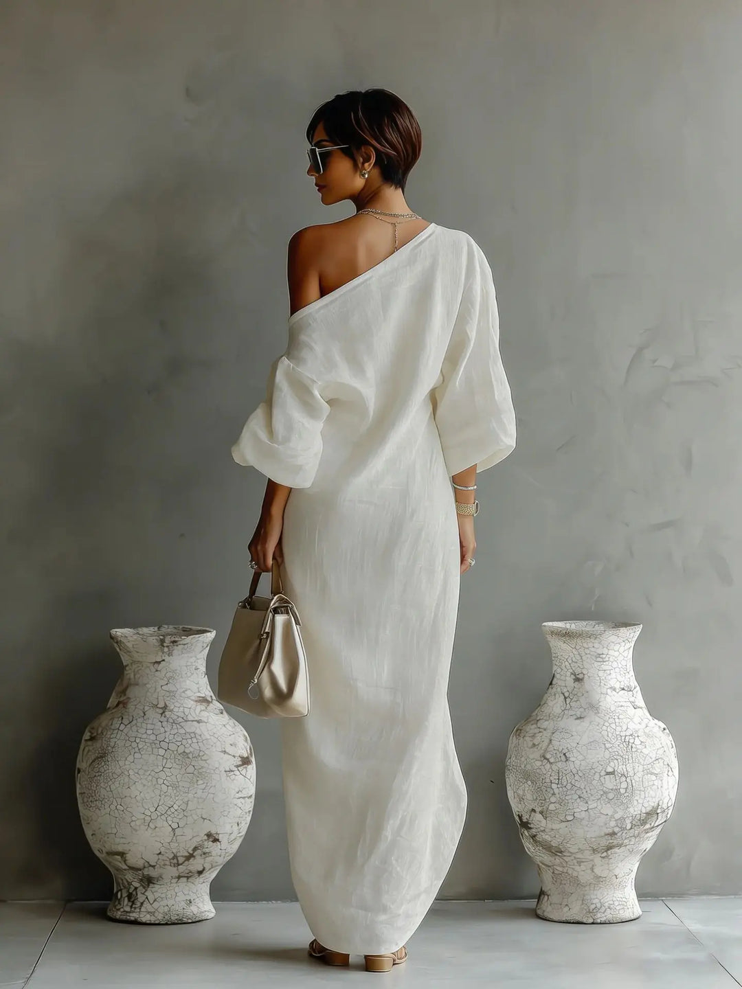 Side angle of asymmetrical one shoulder dress highlighting the flowing batwing sleeve and uneven hemline