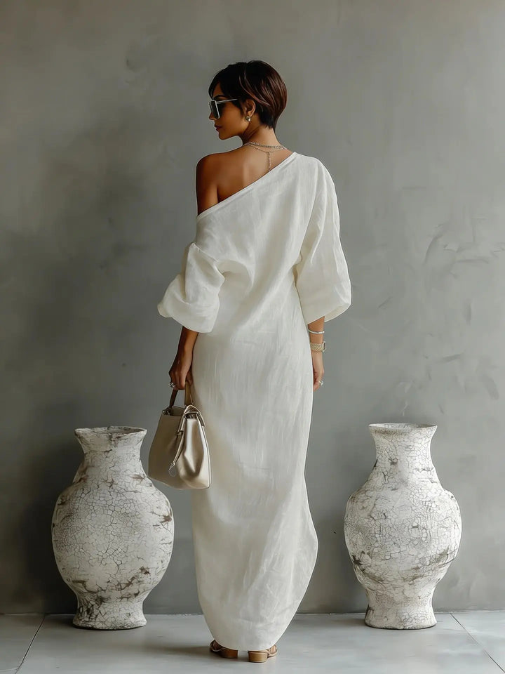 Side angle of asymmetrical one shoulder dress highlighting the flowing batwing sleeve and uneven hemline