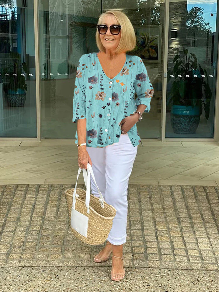 Taupe floral blouse with button placket and three-quarter sleeves paired with white denim.