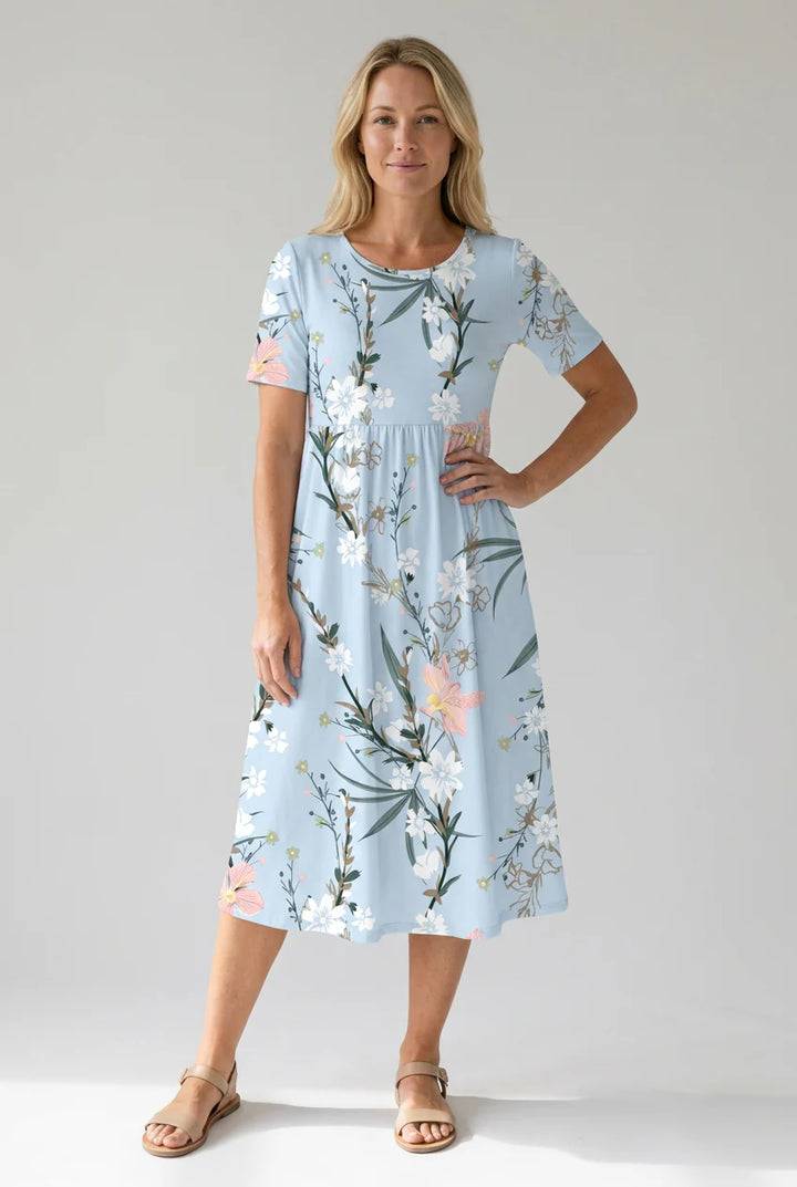 Woman wearing light blue floral midi dress with short sleeves and A-line skirt featuring botanical print