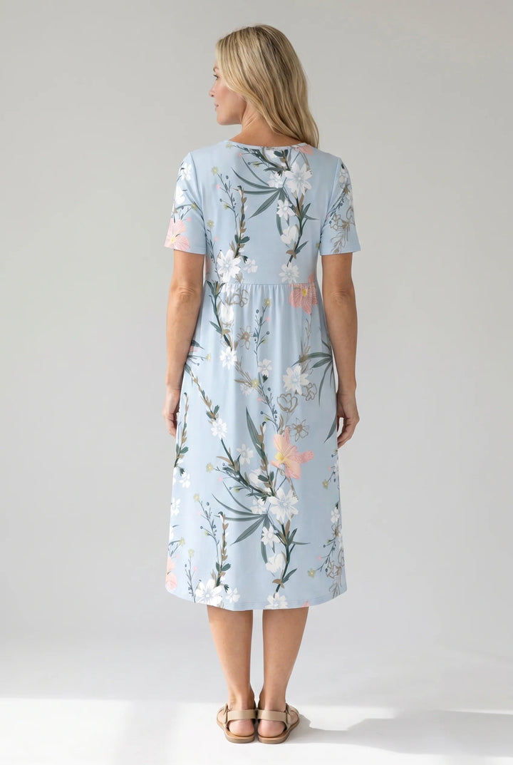 Detail shot of botanical floral print with white flowers and green foliage on midi dress
