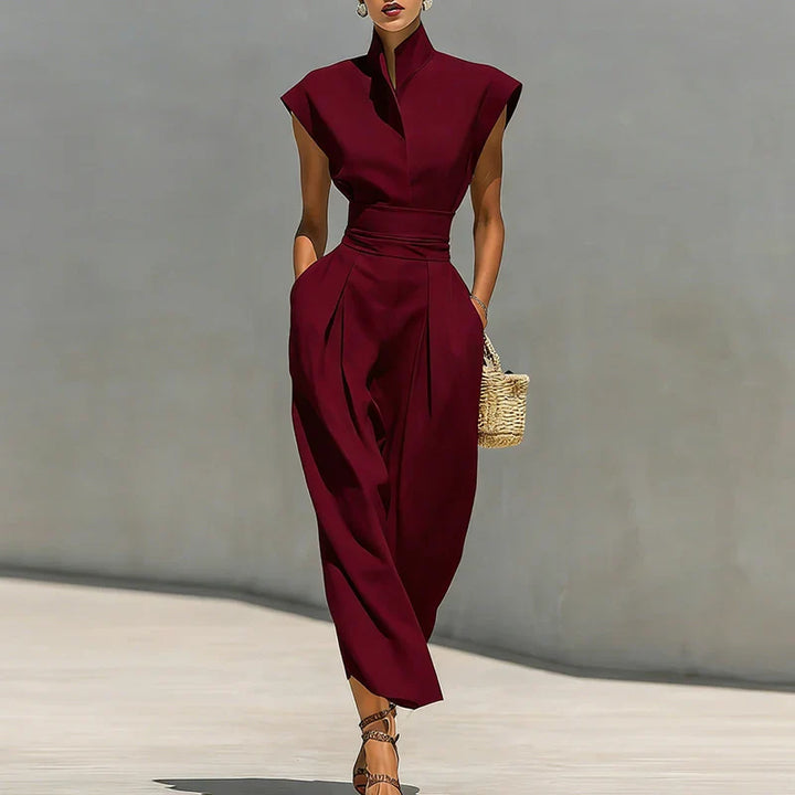 Structured midi dress in burgundy with stand collar and cinched waist on model holding woven clutch