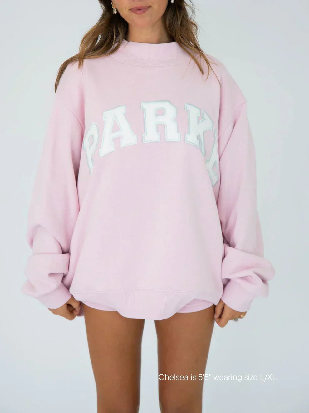 Women's oversized varsity sweatshirt in soft pink with white chenille lettering and crewneck