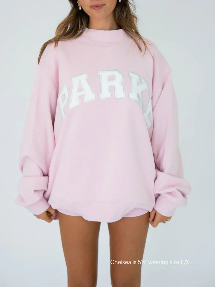 Women's oversized varsity sweatshirt in soft pink with white chenille lettering and crewneck