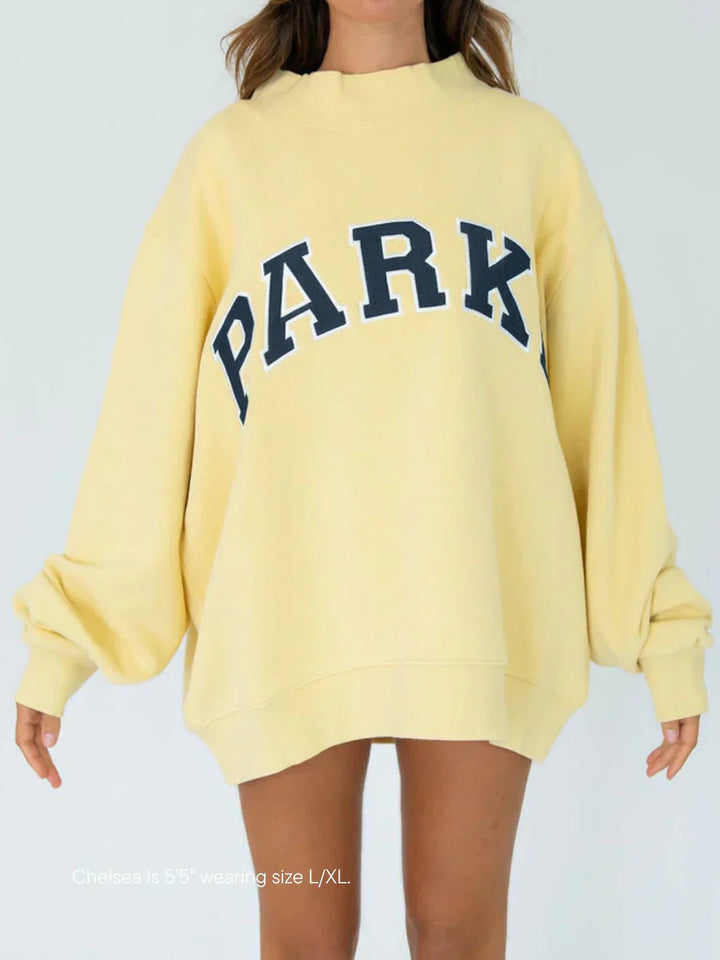 Side view of relaxed fit varsity sweatshirt with dropped shoulders and ribbed cuffs
