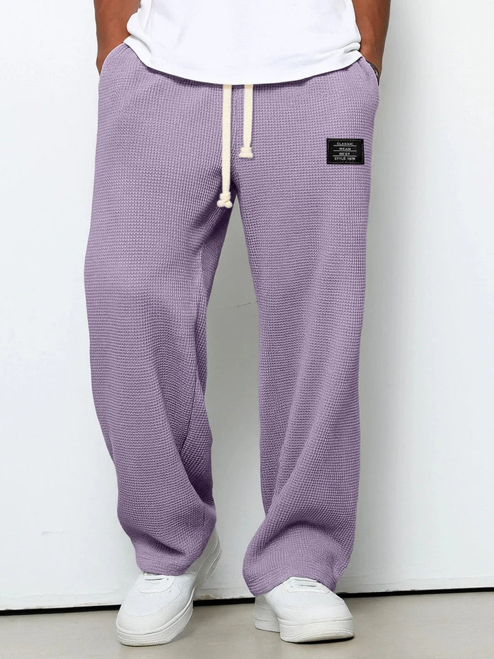 Detail shot of waffle knit fabric texture and small patch branding on joggers
