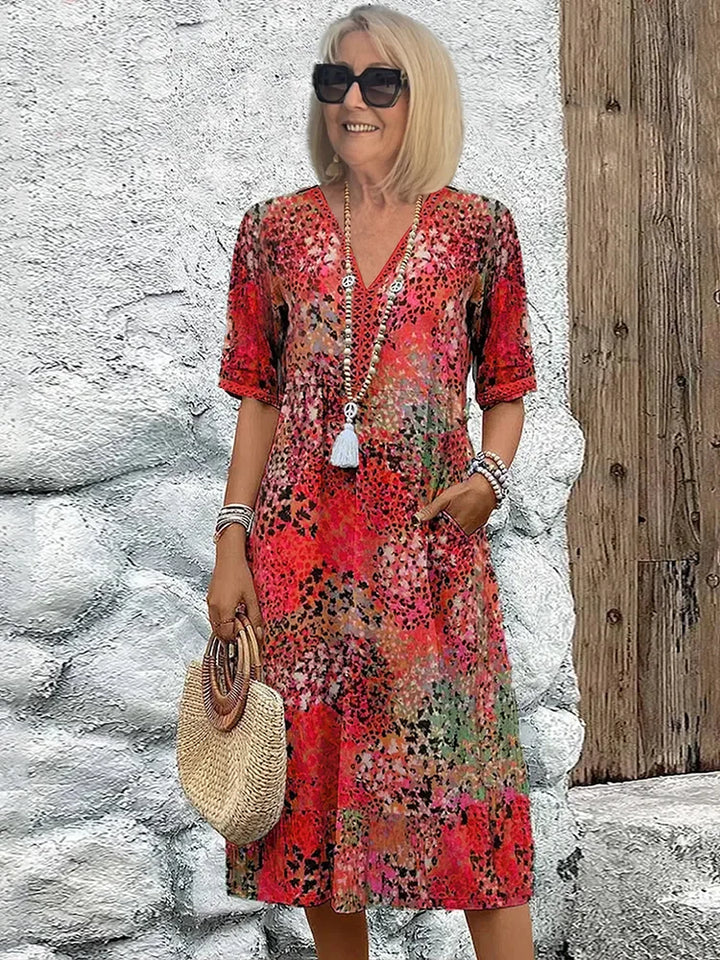 Woman wearing a vibrant floral print cotton summer dress with V-neckline and elbow-length sleeves in midi length