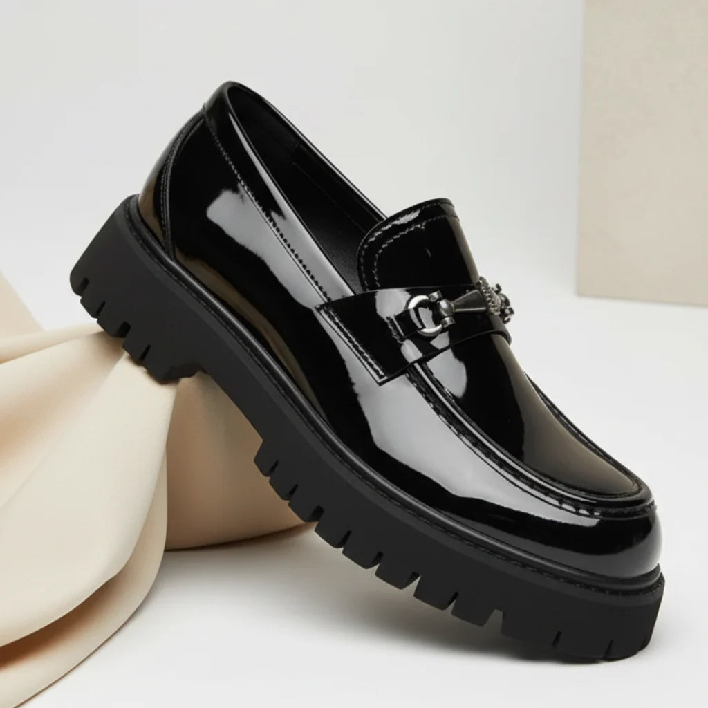 Side profile of black leather dress loafers with lug sole and metal hardware