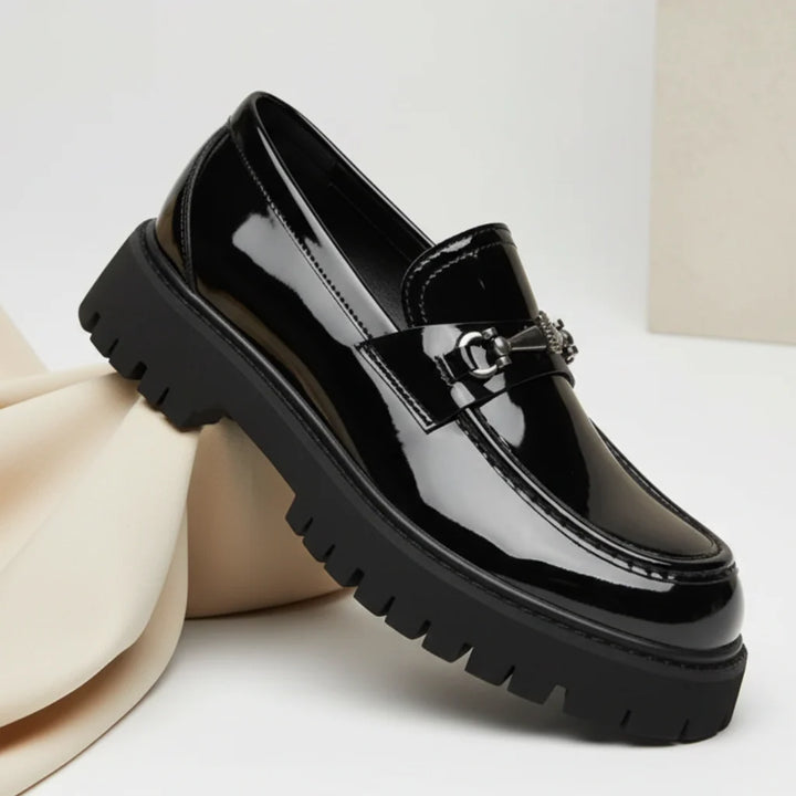 Side profile of black leather dress loafers with lug sole and metal hardware