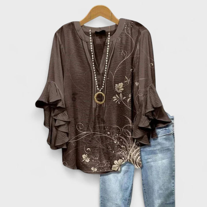 Detail shot of floral print blouse ruffle sleeve panels and decorative neckline button