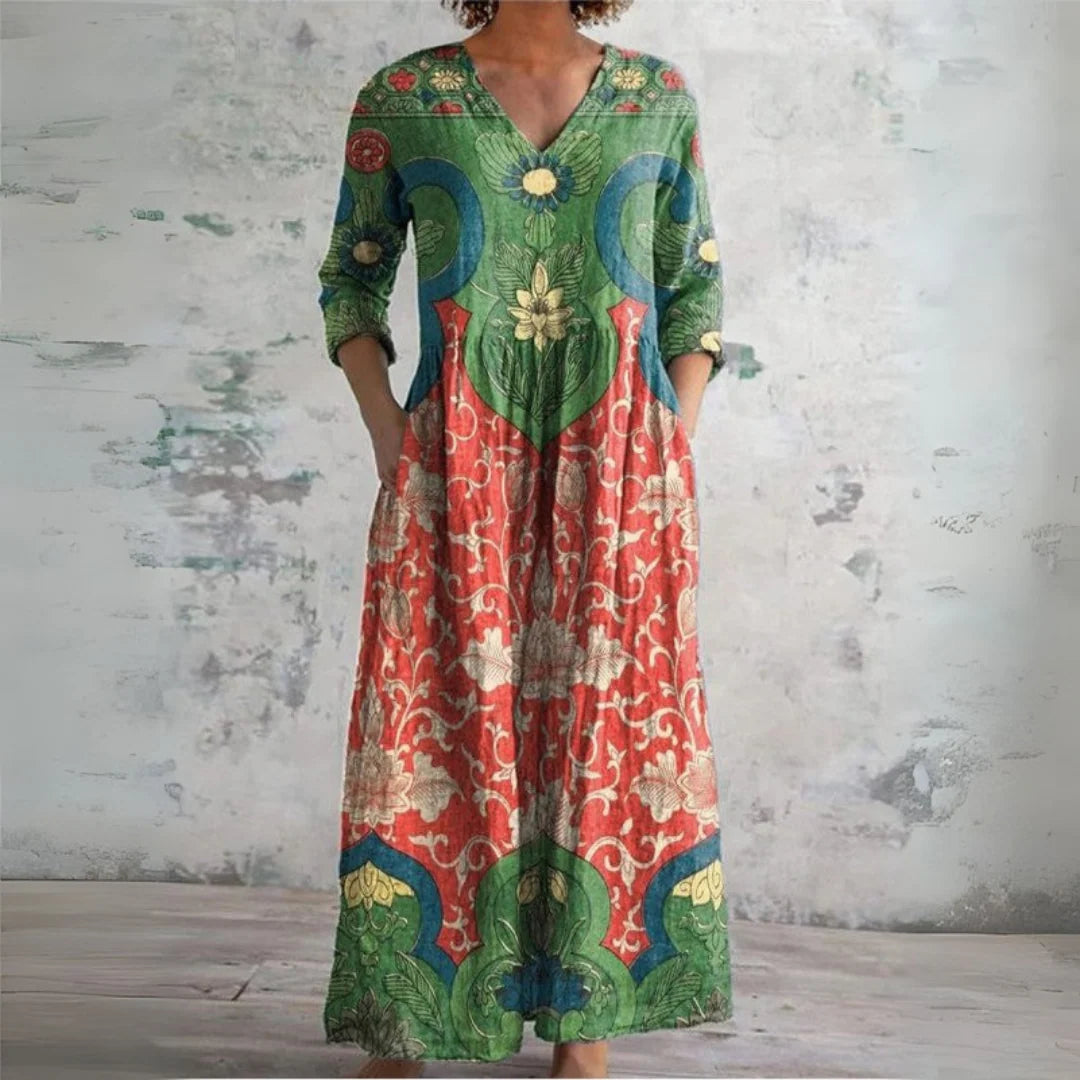 Woman wearing a Floral Maxi Dress with vintage botanical print, V-neckline, three-quarter sleeves, and ankle-length flowing skirt in green, coral, and teal tones