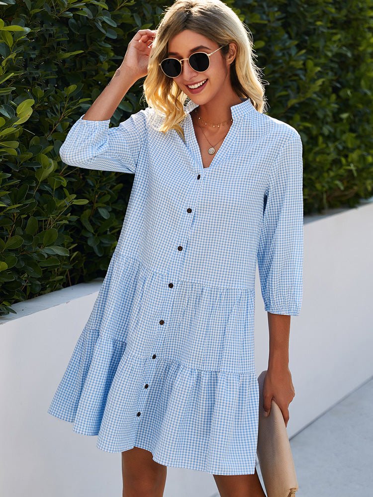 Woman wearing a blue gingham mini cotton summer dress with button front and tiered skirt outdoors