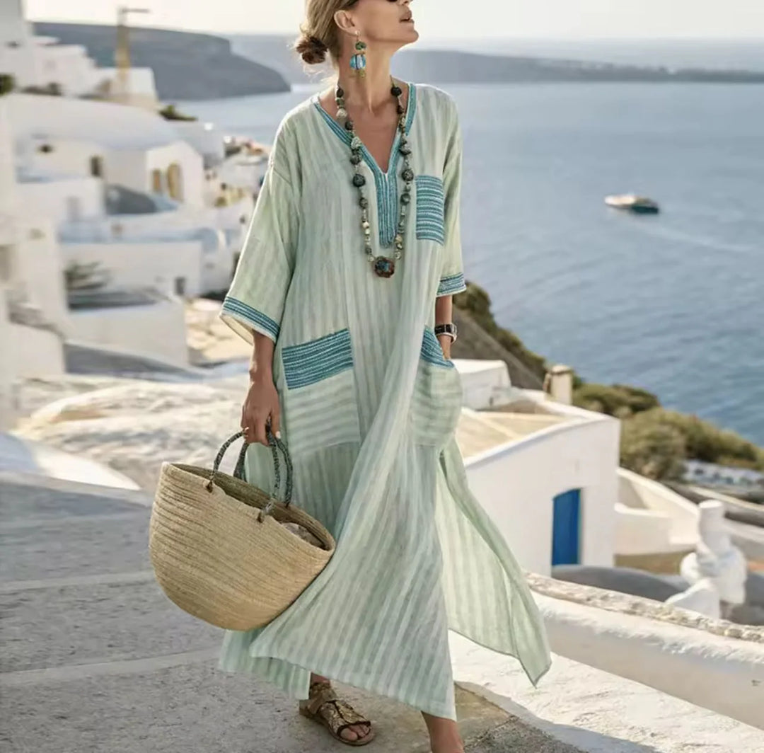 Woman wearing a relaxed fit striped maxi dress with V-neck and three-quarter sleeves in coastal setting