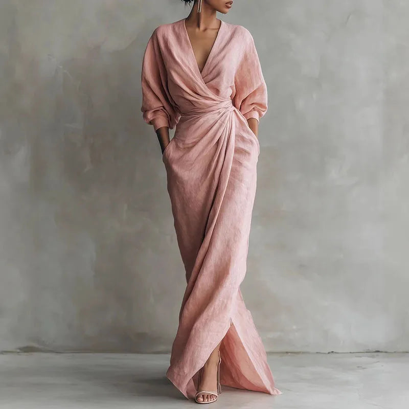Woman wearing a pink V neck wrap waist long dress with draped silhouette and long sleeves