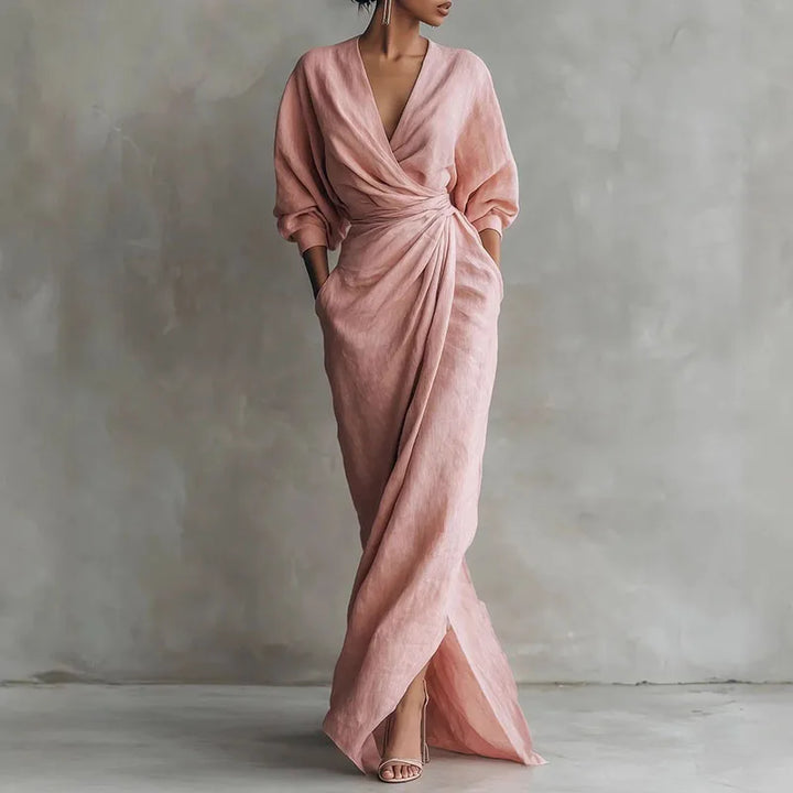 Woman wearing a pink V neck wrap waist long dress with draped silhouette and long sleeves