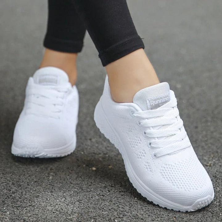 Close-up of white orthopedic walking sneakers showing textured sole and padded collar detail on model's feet