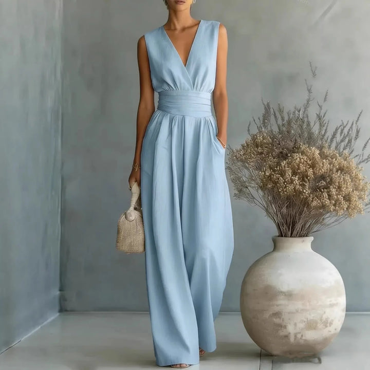 Woman wearing light blue sleeveless V neck jumpsuit with structured high waist and wide leg silhouette