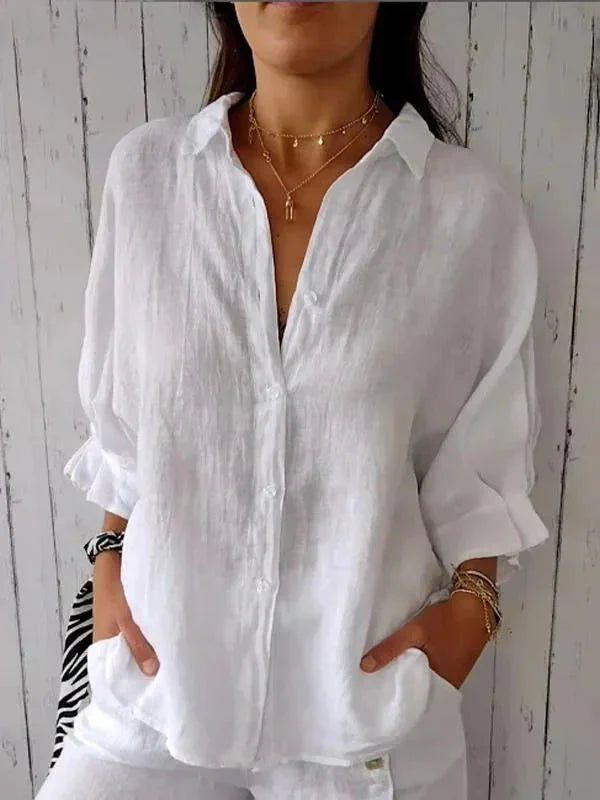 Close-up view of lightweight linen blouse showing V-neckline and button detail with rolled sleeves